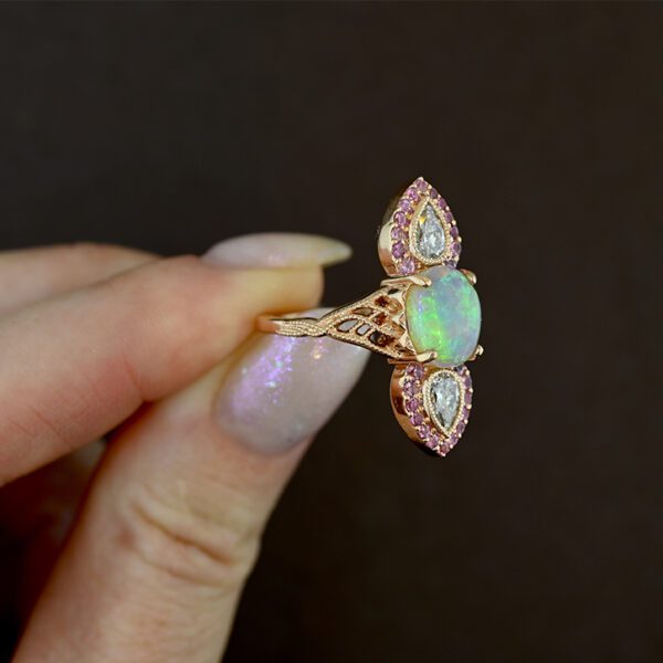 opal-and-pink-sapphire-fairy-ring-aura-in-hand-on-back-background