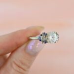 round-moissanite-with-sapphire-accent-engagement-ring-wings-held