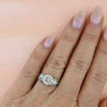 round-moissanite-with-sapphire-accent-engagement-ring-wings-on-hand.jpg